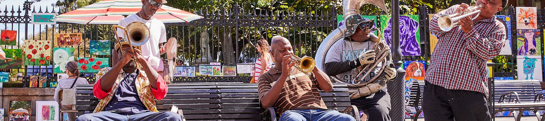 Street musicians play brass instruments on a park bench near a “CHURCH QUIET ZONE” sign, entertaining passersby with lively tunes.