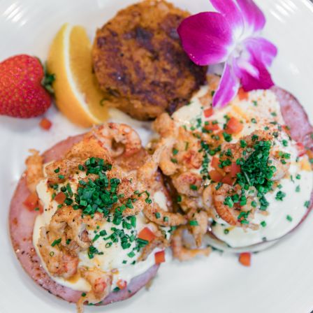 Brunch plate: sausage and eggs with herbs, hash-brown, strawberry, and a purple flower garnish.